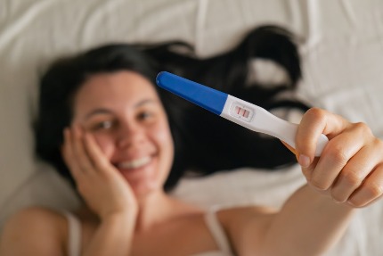 Женщина держит в руке положительный тест на определение беременности.