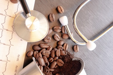 На столе лежит электрокардиограмма, зерна кофе и стетоскоп