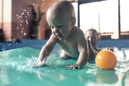 Ребенок в бассейне играет с водой.