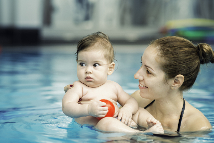Испуганный ребенок на руках у мамы в бассейне.