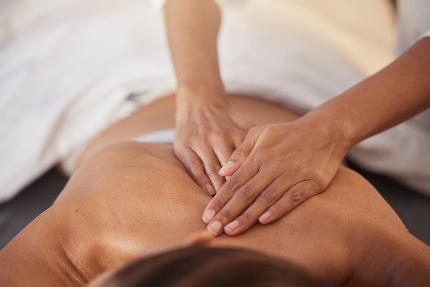Женщине делают массаж грудного отдела позвоночника.