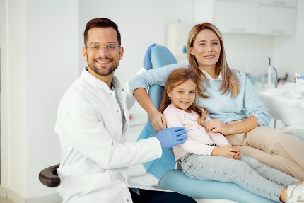 Девочка с мамой в стоматологическом кресле рядом с доктором