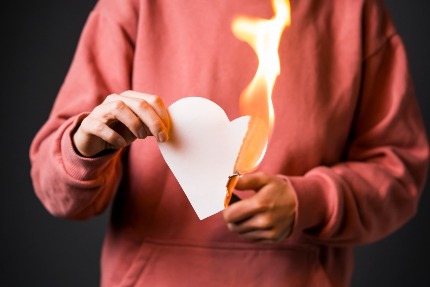 Женщина сжигает сердце из бумаги.