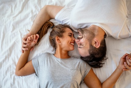 Счастливые мужчина и жнщина лежат на кровати.