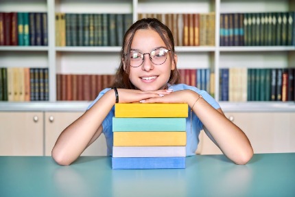 Девочка-подросток со стопкой книг.