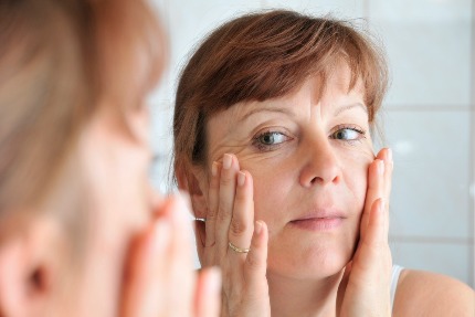 Женщина среднего возраста смотрится в зеркало.