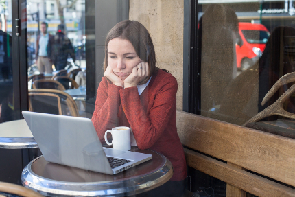 Женщина сидит в кафе за ноутбуком