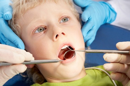 Стоматолог осматривает рот ребенка.