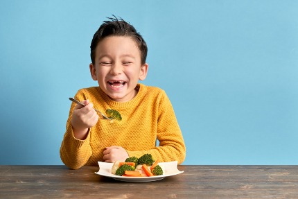 Мальчик ест брокколи