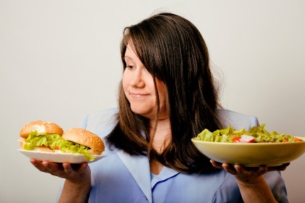 Женщина выбирает между гамбургером и салатом