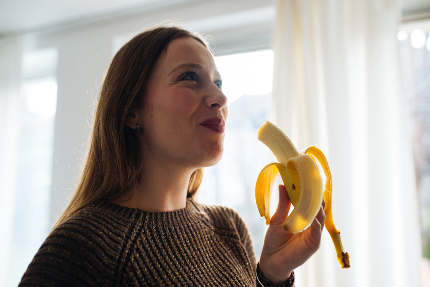 Девушка ест банан.