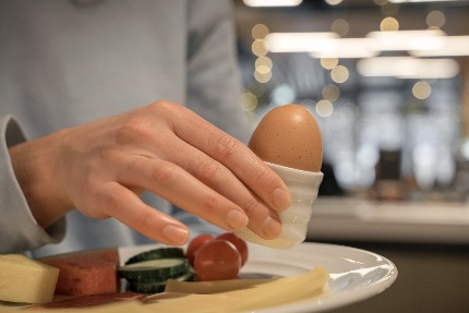 Женщина держит подставку с вареным яйцом.