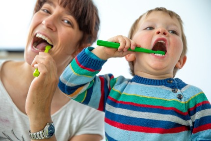Мама показывает маленькому сыну как чистить зубы.