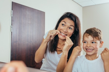 Мама показывает сыну, как пользоваться зубной нитью.