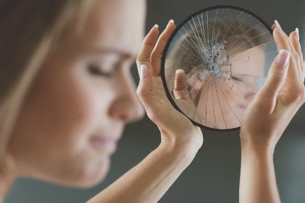 Женщина отвернулась от своего отражения в разбитом зеркале.